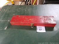 Closed red metal case on green surface
