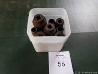 Plastic container holding nine large steel square drive sockets on dark floor surface with auction lot tag number 58 visible.