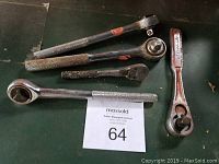 Set of four socket wrenches on a dark surface showing varying sizes and condition