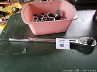 Heavy duty ratchet wrench laid out next to a pink container holding multiple sockets