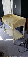 Vintage yellow painted wooden desk or vanity showing the overall shape and wear.