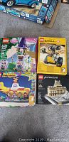 Four sealed boxed LEGO sets displayed on carpet: Rapunzel tower, WALL·E, Yellow Submarine, Louvre