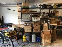Full view of charcoal metal shelving unit with five shelves loaded with various household items including boxes and appliances.