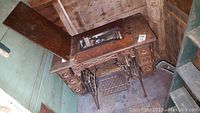 Full view of antique sewing machine cabinet with open top lid showing the sewing machine inside and six drawers.