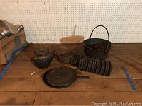 Full view of all cast iron cookware items including kettle, pots, skillet, and cornbread stick pan.