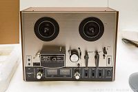 Front view of AKAI 4000DS Mk-II stereo tape deck on table, shows dual reel spindles, control knobs and VU meters