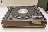 Front angled view showing the full Garrard turntable with wood finish sides and circular platter with rubber mat, metal controls, and tonearm.