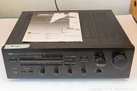 Front view of Yamaha RX550 receiver showing tuning dial, knobs, and included manual.