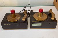 Front view of two vintage RCA Victor Model 9JY record players showing black base, gold tone turntables with red spindle caps and gold tone tonearms.