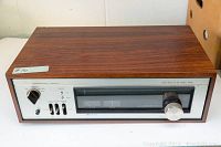 Front view of unit showing wood veneer cabinet, metal faceplate and analog tuning display