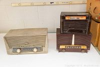 Three vintage radios placed on a shelf showing Motorola MK66X beige radio and other two radios in brown bakelite cases.