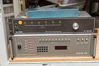 Front view of two stacked AV equipment units: top is Bell Howell multi-terminal switch unit HI-BEAM with input selection buttons and control knob; bottom is Barco video selector with buttons and LED display.