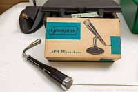 Grampian DP4 microphone in front of its original box showing the microphone body and packaging.