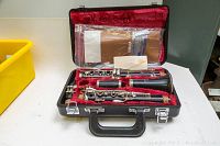Open view of Yamaha clarinet inside black hard case with red velvet liner, showing clarinet parts and included documentation and accessories.
