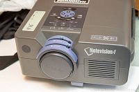 Top angled view of the Sharp Notevision 4 projector showing lens cover and control panel with buttons and dials.