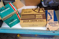 Three boxed items on a workbench: Hanimex E200 Movie Editor, Kalart Editor Viewer Eight, and A Lite movie light