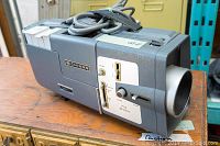 Vintage Chinon zoom lens camera body showing side view with control knobs and F1.5 20-32mm lens marking.