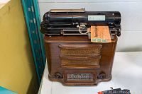 Overall view of the Todd Protectograph check writer atop the Westinghouse wooden radio, showing general shape and labels.