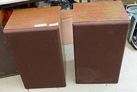 Front view of two vintage speakers with wood veneer finish and brown fabric grills.