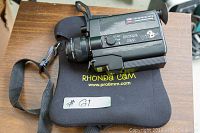 Rhonda Cam Pro 8mm film camera placed on its branded carrying bag with shoulder strap visible.