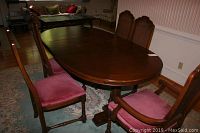 Six wooden dining chairs around an oval dining table in a dining room