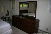 Full view of dresser with attached large mirror, showing front and part of bedroom surroundings.