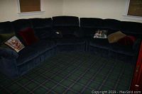 Three-piece blue sectional couch with plush fabric and decorative pillows arranged in corner shape on patterned carpeted floor.