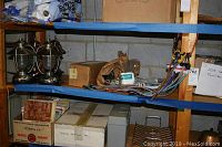 Shelving unit displaying 2 copper-colored lanterns and 2 silver-colored lanterns, assorted bungee cords and boxes.