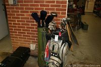Two golf bags with sets of golf clubs inside placed in a garage against a brick wall, showing the overall lot contents.