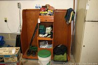Overview of wooden golf cabinet with various golf accessories arranged on shelves and below, including gloves, balls, mats, and umbrella.