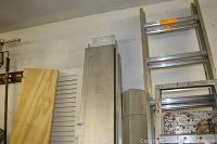 Photo showing the metal ramp leaning vertically against a wall among other hardware items.