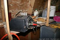 Battery charger and various hand tools and gloves on wooden shelves in attic