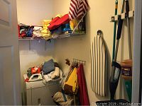Laundry room corner with washer, dryer, blankets, folded towels, and ironing equipment visible.
