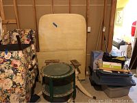 Photo showing folded kitchen table with detachable leaf in light wood finish beside round glass-top side table with green decorative paint.