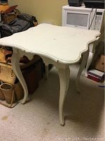White coffee table with curved edges and legs showing paint wear.