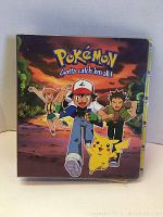 Front cover of the Pokémon card binder showing Ash, Pikachu, Brock, and Misty artwork with the phrase 'Gotta catch 'em all!'