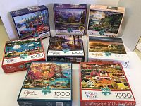 Photo showing all 8 Buffalo brand 1000-piece jigsaw puzzles stacked together, featuring scenic artwork on each box
