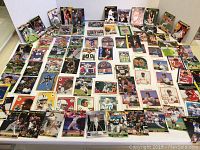Overview of laid out collection of sports trading cards from multiple sports including football, baseball, basketball and hockey.