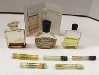 Photo of 3 tiny perfume bottles and 5 small perfume vials arranged on a surface with a Michael Kors promotional card spray vial included