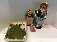 Five vintage assorted dolls grouped with two colonial dolls in green felt outfits in a box and three standing dolls including Byer's Choice and Monticello Bell doll.