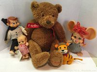 Full lot view showing 5 toys including teddy bear, dolls, coin bank, and plush lion