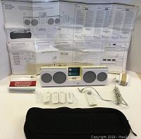 Full lot including Logitech Pure-Fi Anywhere speaker dock, wired remote control, four plastic white iPod adapters, power adapter, instruction manual unfolded behind, small red booklet, and black zippered soft carrying case in front