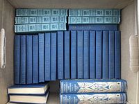 Box with multiple old hardcover books arranged showing spines. Light blue books labeled 'How to Speak in Public' in top row, twenty dark blue books in middle and bottom rows, some of these with gold text and decorative designs, likely The Pocket University series and French Cathedrals and Chateaux volumes.