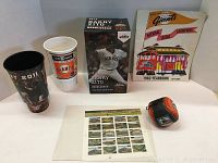 Photo of all items together: 2 collectible cups, bobblehead in box, yearbook, stamp sheet, and soft baseball.