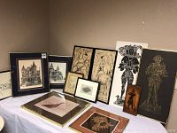 Full view of all 11 framed artworks on a table including horses, knights, architectural drawings, and shell art.