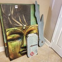 Grouped image showing golden Buddha canvas and other prints stacked along with wooden sculpture