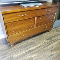 Full frontal view of the midcentury vintage solid wood dresser showing drawer configuration and handles.