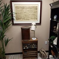Overall view of ticket cabinet, cylindrical luggage, lamp and framed print