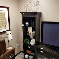 Tall dark wood shelving unit with various decor items including the spherical wire piece, car clock, glass jars, and more.
