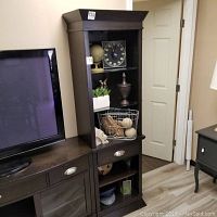 Full view of the wooden shelf combined with a lower cabinet, showing dark wood finish, open shelves behind glass doors, and drawer with metal handle.